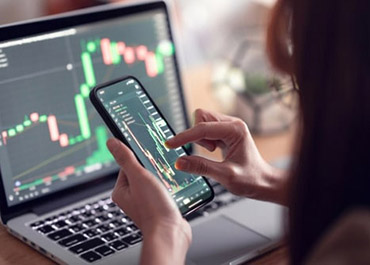 Analyzing crypto charts on laptop & phone. Learn defense strategies for cryptocurrency fraud charges.