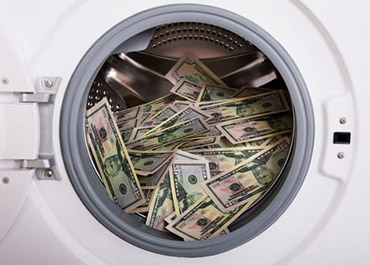 Washing machine drum filled with US dollar bills, symbolizing money laundering.