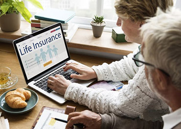 People reviewing life insurance on laptop. Learn about life insurance fraud & legal defenses.