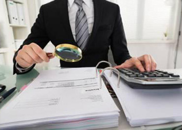 Accountant with magnifier & calculator. Facing tax fraud in Texas? Get expert legal defense now.