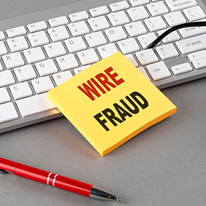 Yellow sticky note 'WIRE FRAUD' on keyboard, for Dallas wire fraud lawyer.