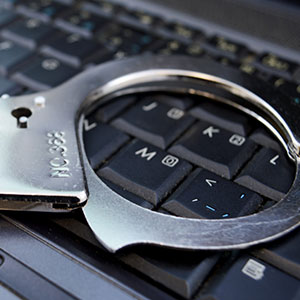 Handcuffs resting on a laptop keyboard, symbolizing cybercrime.