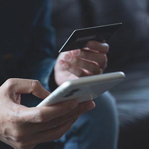 Hands with credit card and smartphone for secure Dallas bank fraud defense.