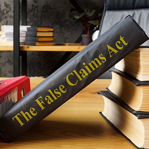 Large book titled 'The False Claims Act' on a wooden desk, symbolizing legal expertise.