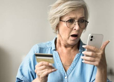 Shocked senior with phone & credit card, highlighting elder fraud & harsher sentencing implications.