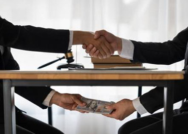 Men shaking hands, exchanging money. Symbolizes bribery, money laundering, and illicit deals.