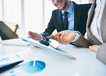 Business professionals reviewing regulatory compliance documents on tablet  